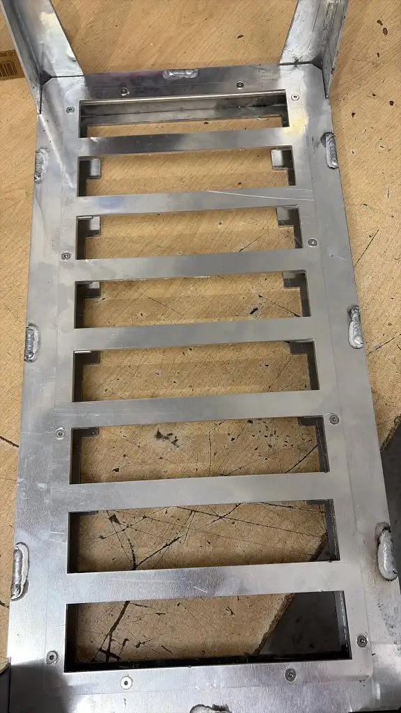 Top view of a bespoke aluminium tray with evenly spaced rectangular slots in the base plate