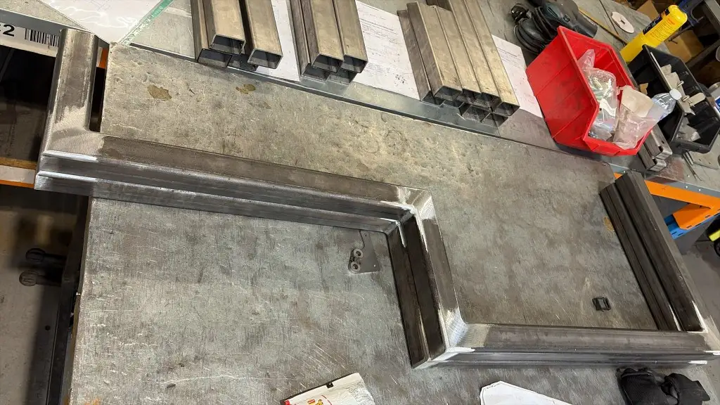 Early fabrication of a garden pond staircase stringer in square steel tube, with ground welds, on the workshop bench