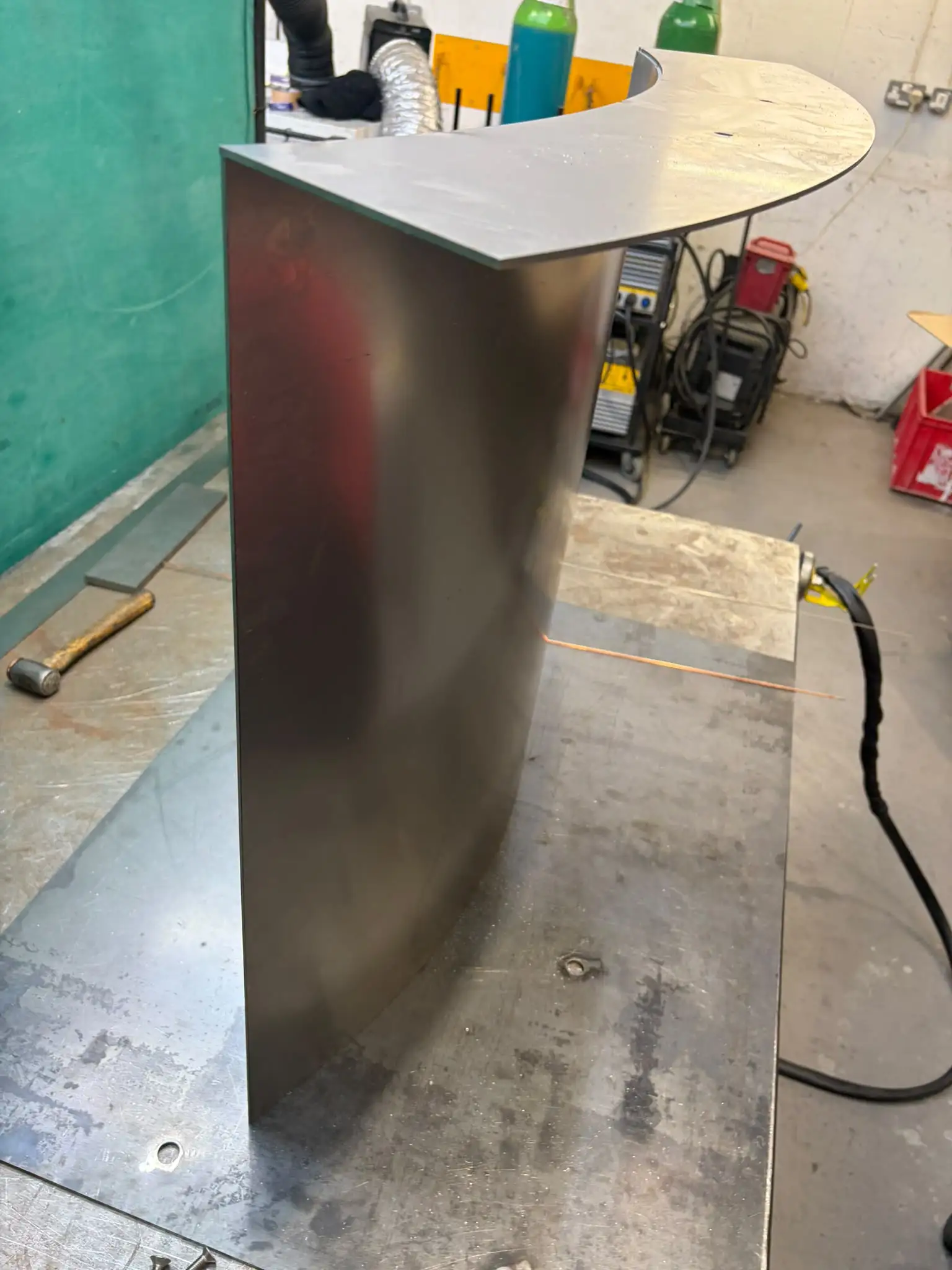Curved dining table base upright with its top plate fitted, on the welding table
