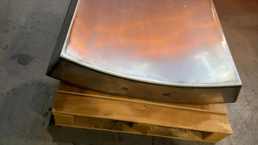 Close-up of a hand-dressed curved dining table base with blended edges, on a pallet