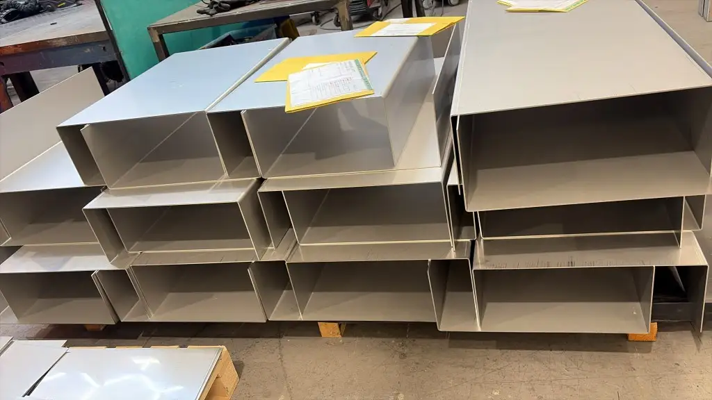 Stacks of folded stainless magnet cases in production, yellow job folders marking the current stage
