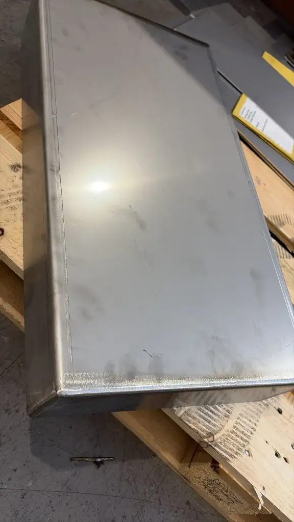 A welded stainless magnet case on a pallet, with further sheet and a job folder behind