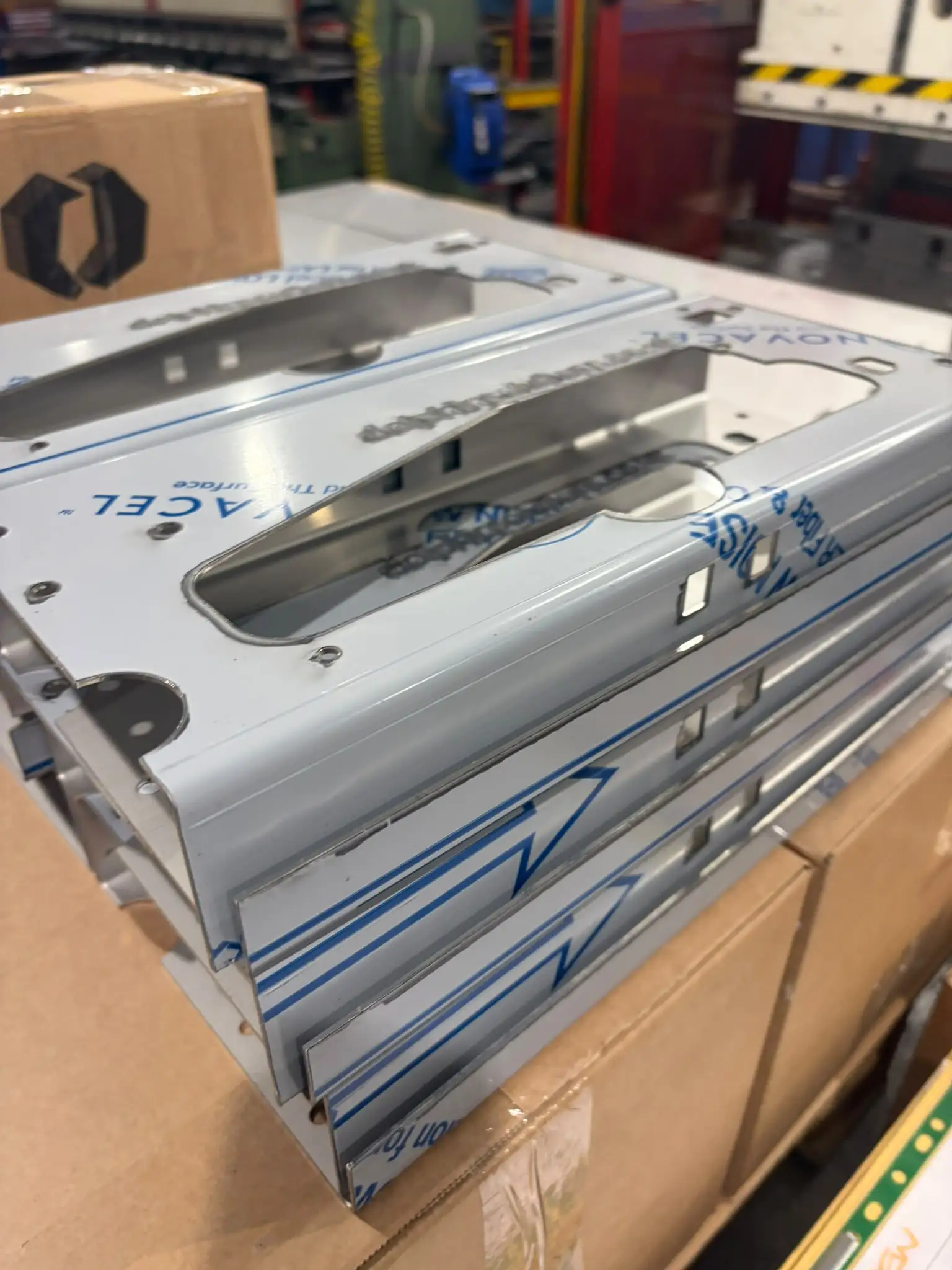 Close-up of laser-cut and folded stainless panels with a large centre cutout and protective film still on