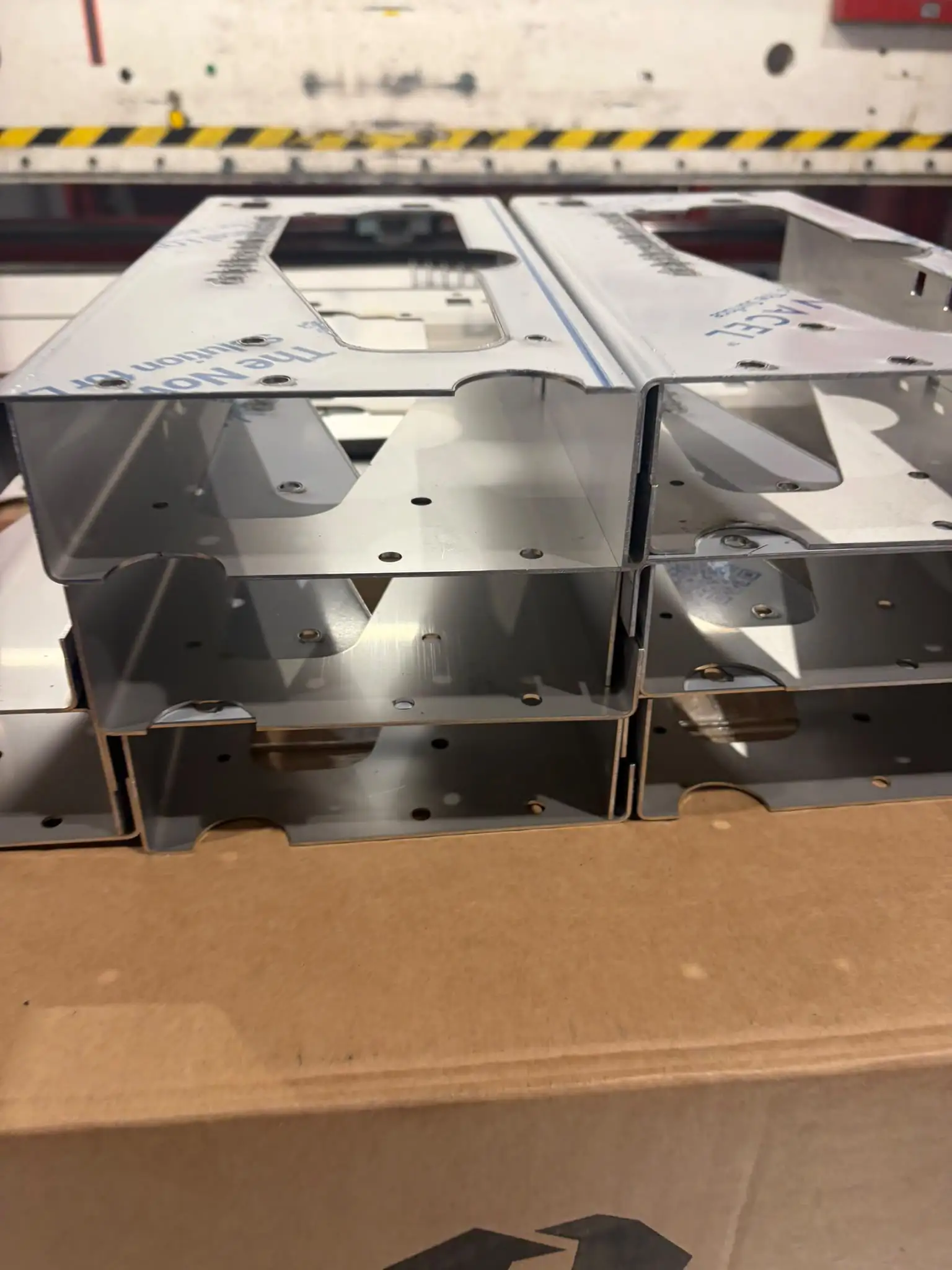 Complex channel brackets in stainless steel, stacked on cardboard after folding
