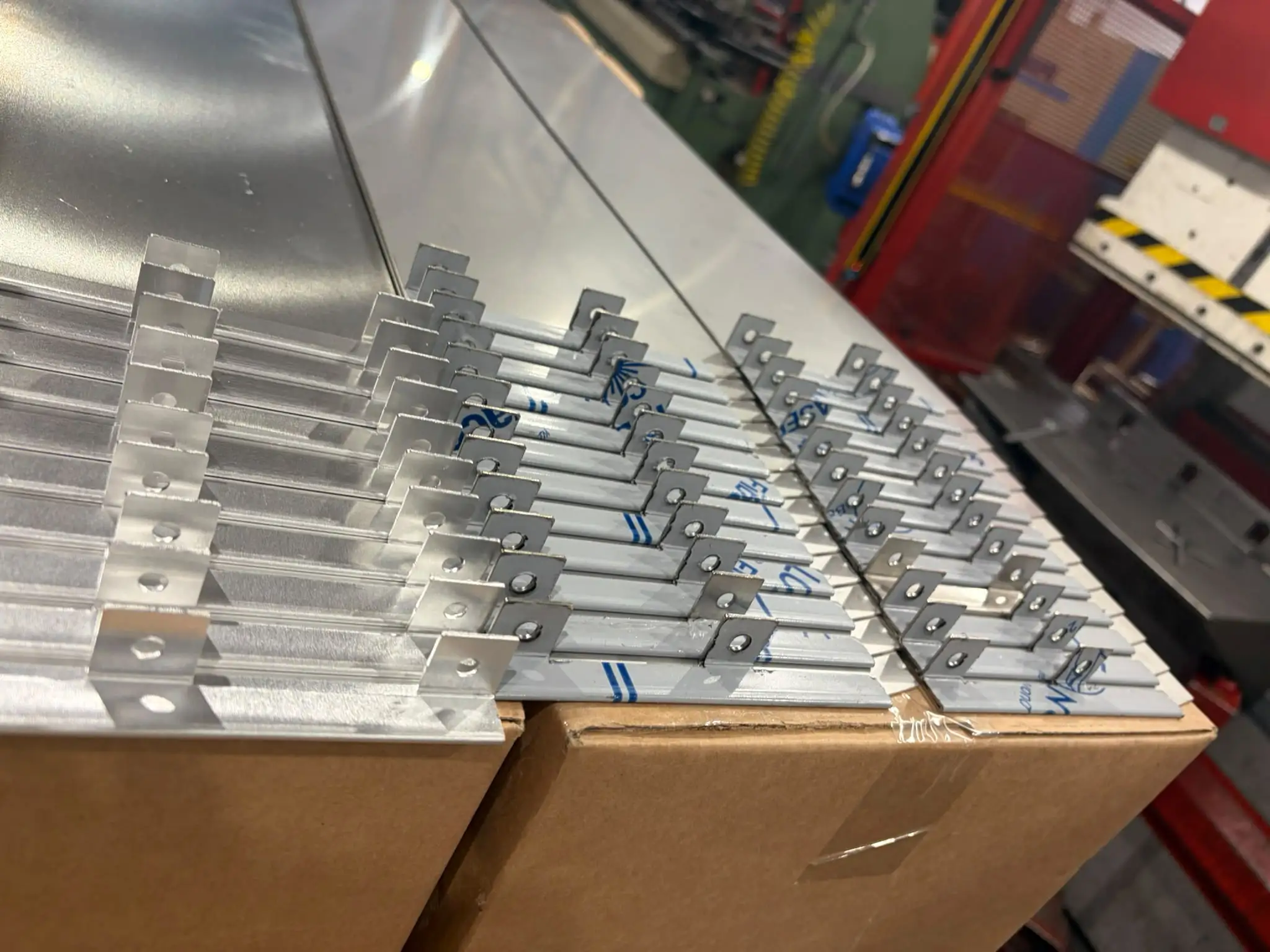 Rows of small stainless brackets with upright tabs and holes, ready for the next stage