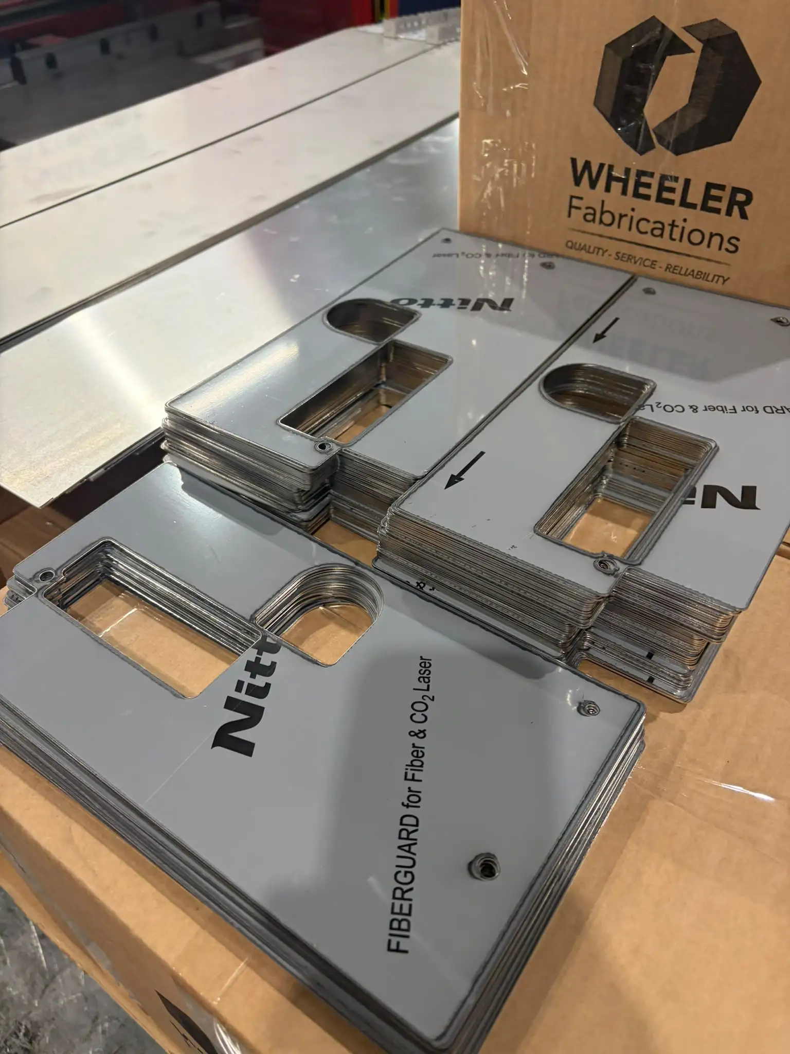 Stacks of flat laser-cut stainless plates with rectangular openings and protective film