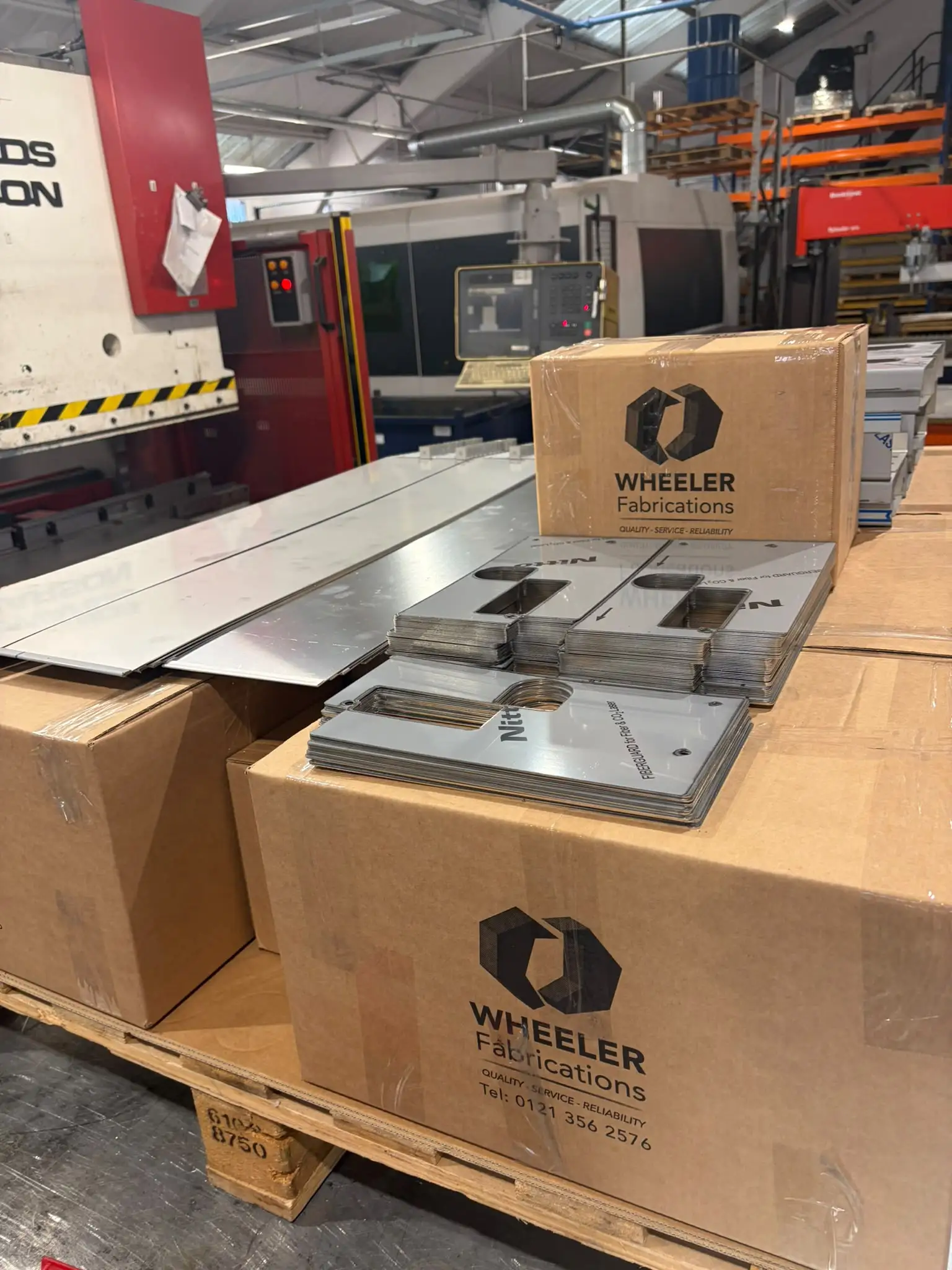 Finished stainless bathroom parts stacked on branded Wheeler Fabrications boxes on a pallet