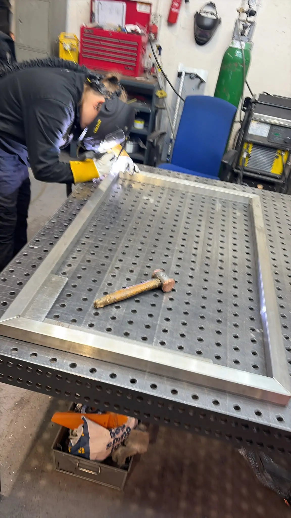Fabricator TIG welding a stainless steel rectangular frame on a fixture table