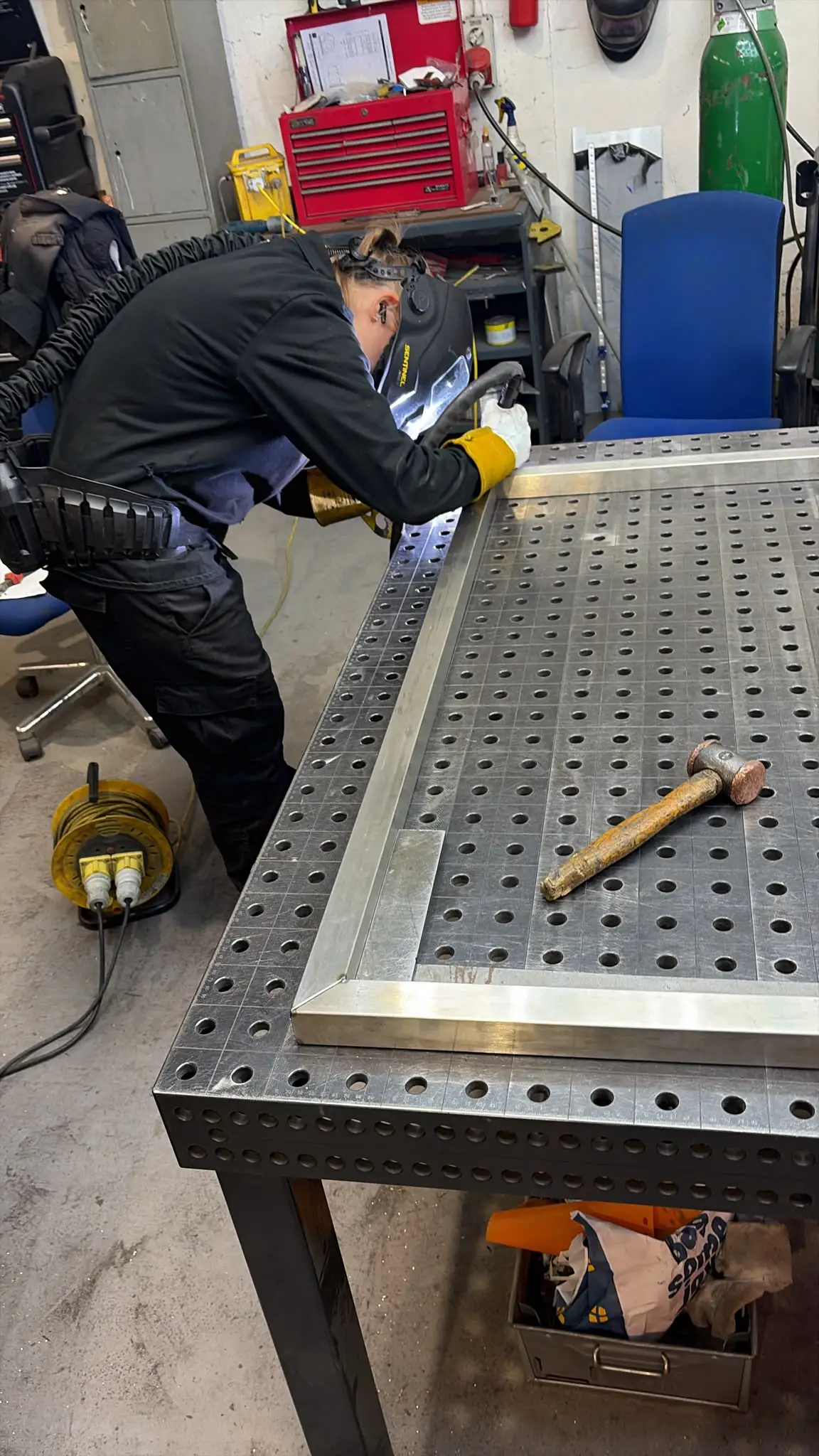 TIG welding in progress on a stainless steel frame with a powered air helmet