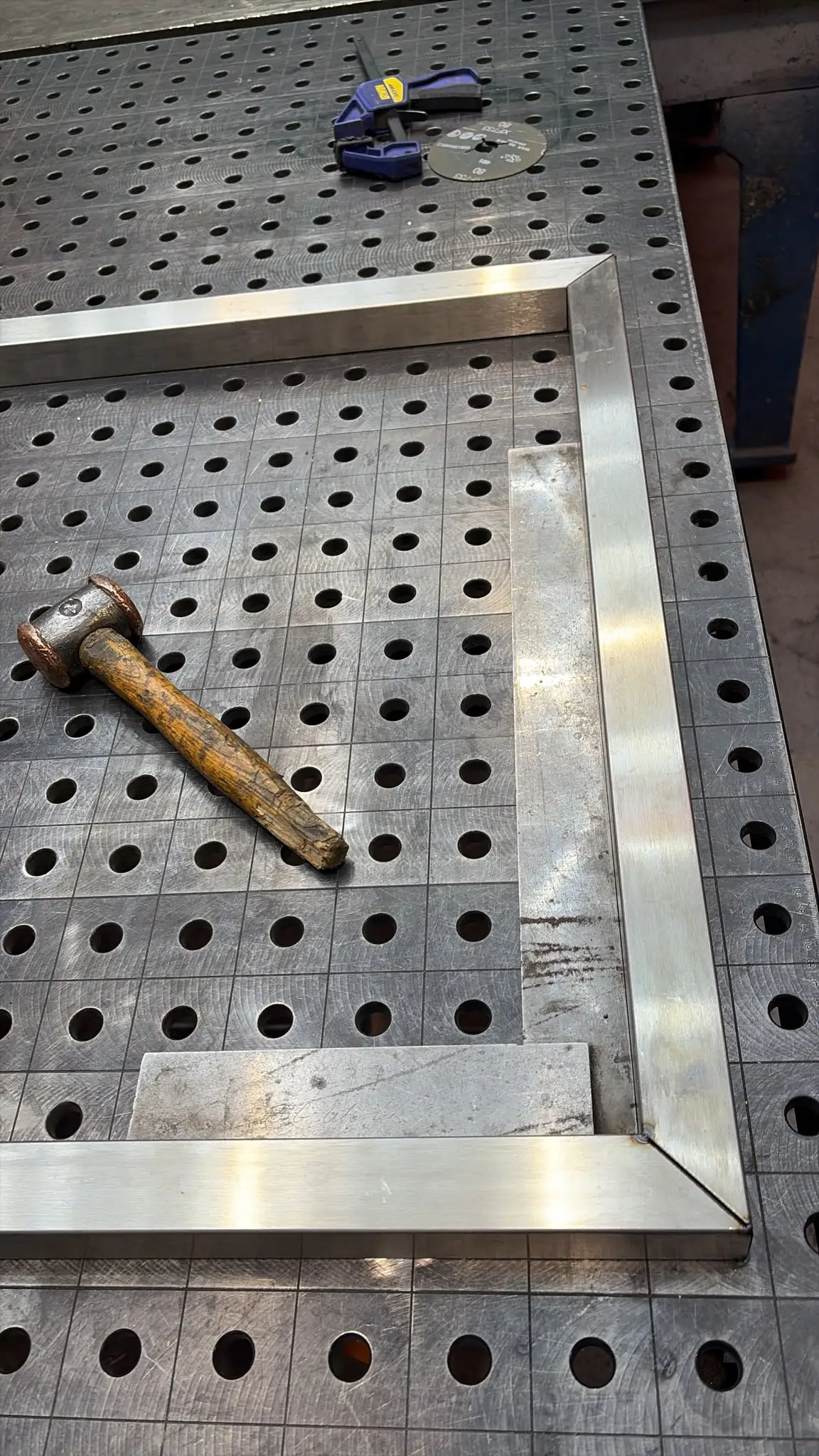 Mitered corner of a stainless frame checked with a square on the fixture table